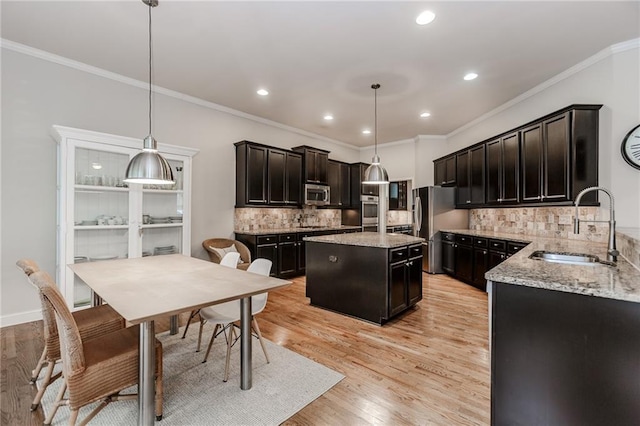 kitchen featuring a sink, appliances with stainless steel finishes, crown molding, decorative backsplash, and a center island