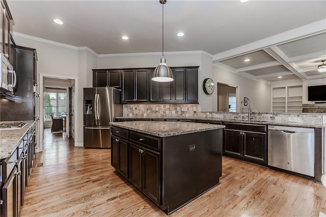 kitchen featuring appliances with stainless steel finishes, a sink, light wood-type flooring, a kitchen island, and crown molding