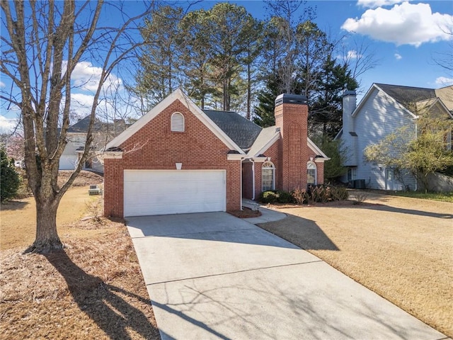 view of front facade with brick siding, a front yard, a chimney, a garage, and driveway