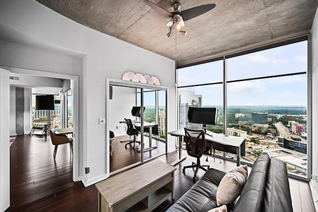 living room with a ceiling fan, a city view, a wall of windows, baseboards, and dark wood-type flooring