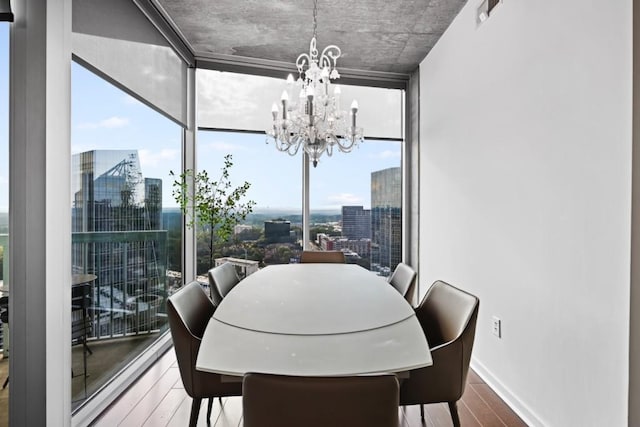 dining room featuring wood-type flooring, a healthy amount of sunlight, an inviting chandelier, and a wall of windows