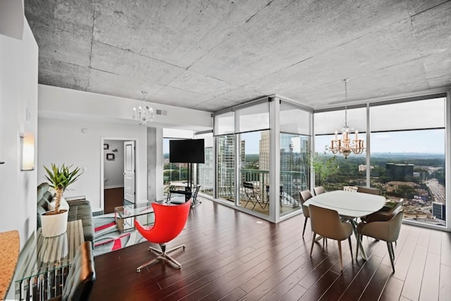dining area featuring wood finished floors, a chandelier, and a wall of windows
