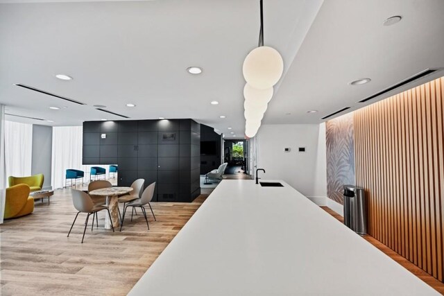 interior space with recessed lighting, light wood finished floors, modern cabinets, a sink, and decorative light fixtures