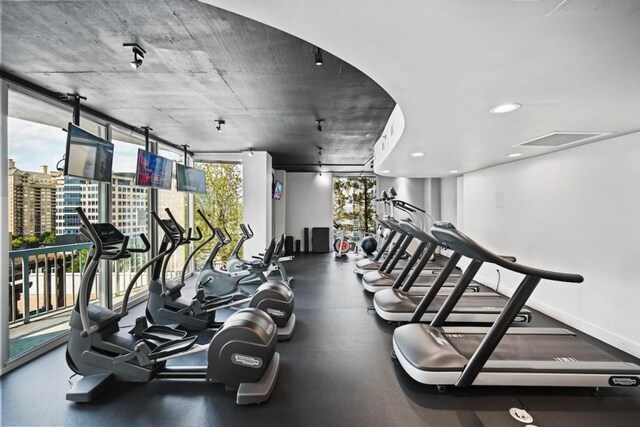 workout area featuring recessed lighting, plenty of natural light, and baseboards