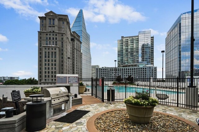 view of patio / terrace featuring a city view, a community pool, a grill, and fence