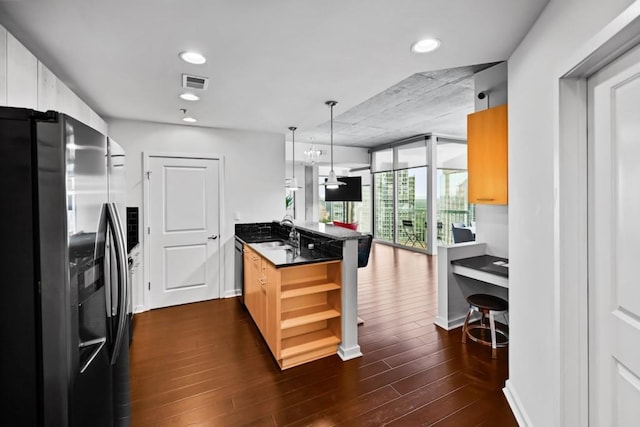 kitchen with refrigerator with ice dispenser, hanging light fixtures, kitchen peninsula, floor to ceiling windows, and dark wood-type flooring