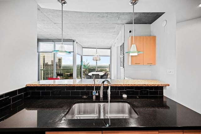 kitchen with hanging light fixtures, dark stone counters, and a sink