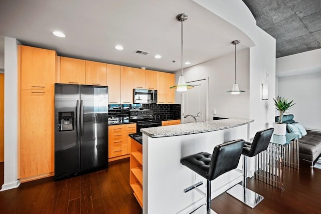 kitchen with appliances with stainless steel finishes, dark wood-type flooring, light brown cabinets, and decorative light fixtures