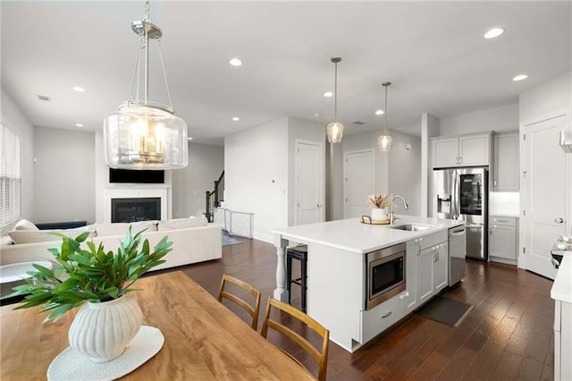 kitchen with open floor plan, appliances with stainless steel finishes, a fireplace, and a sink