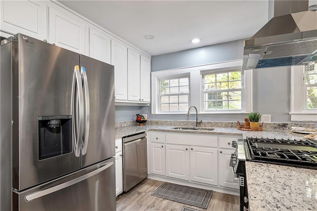 kitchen with appliances with stainless steel finishes, white cabinetry, a sink, and island exhaust hood