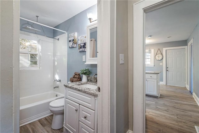 bathroom with baseboards, toilet, wood finished floors, vanity, and shower / bathing tub combination