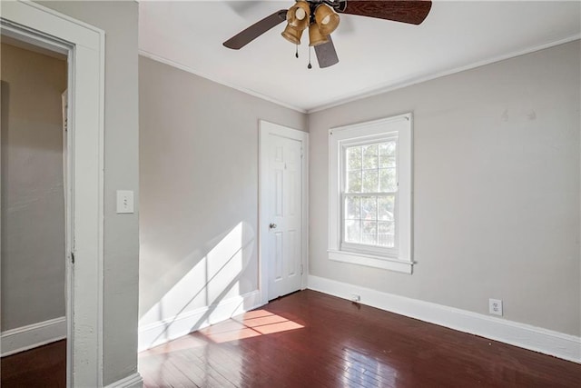 empty room with a ceiling fan, baseboards, dark wood-style flooring, and ornamental molding