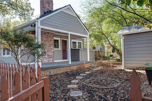 exterior space with a chimney, fence, and an outbuilding