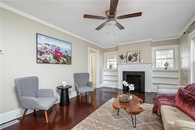 living area with a fireplace, baseboards, dark wood finished floors, and crown molding