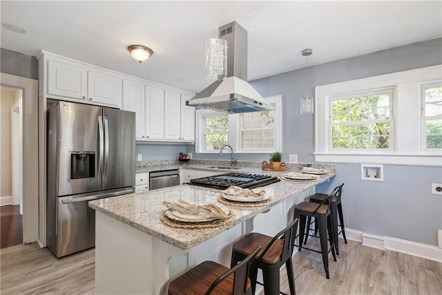 kitchen featuring white cabinets, a breakfast bar area, hanging light fixtures, island exhaust hood, and stainless steel appliances