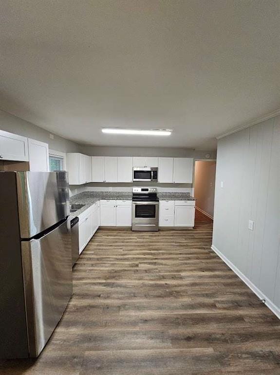 kitchen featuring a sink, light stone counters, appliances with stainless steel finishes, white cabinets, and dark wood-style flooring