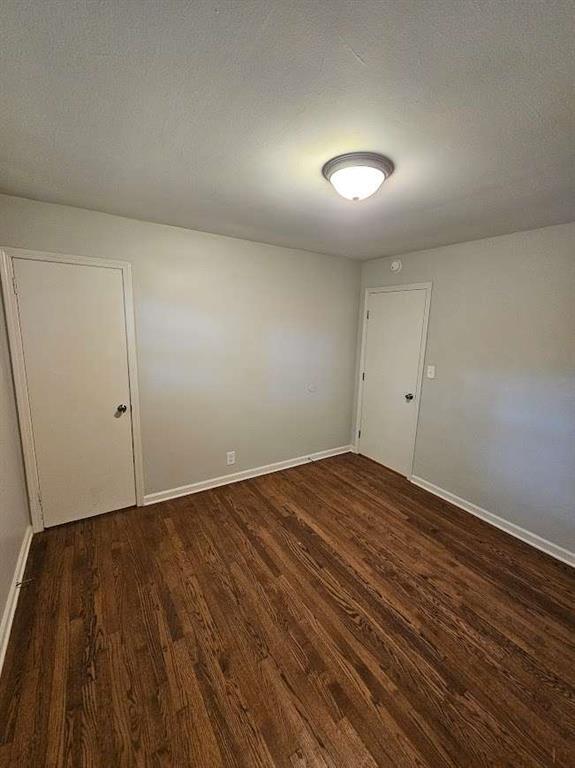 spare room with baseboards, a textured ceiling, and wood finished floors