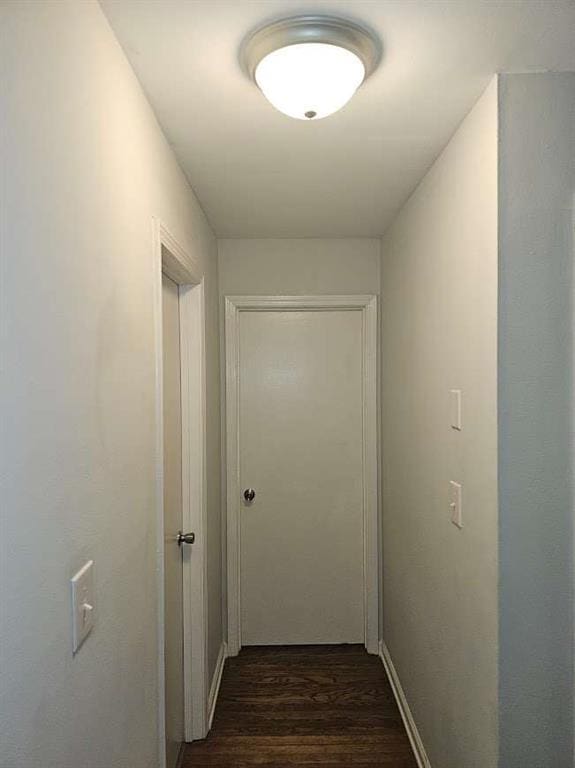 corridor with baseboards and dark wood-type flooring