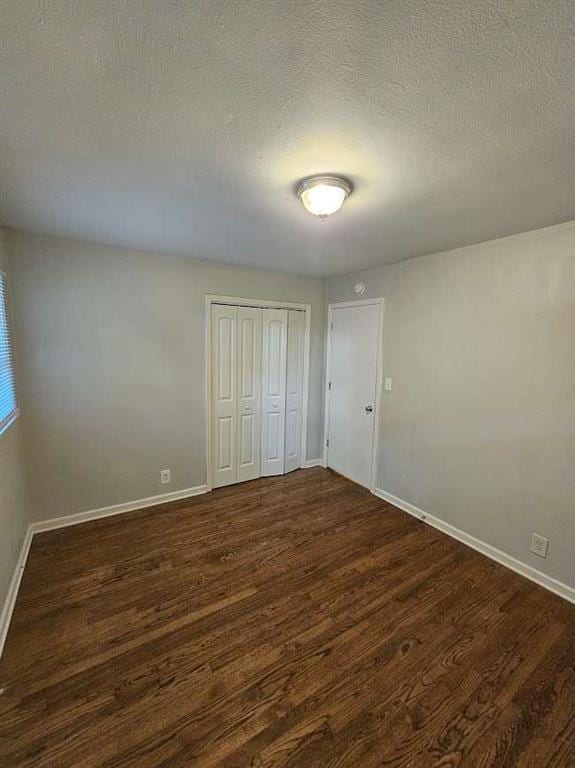 unfurnished bedroom featuring baseboards, wood finished floors, a closet, and a textured ceiling