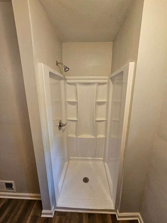 bathroom featuring a shower, visible vents, baseboards, and wood finished floors