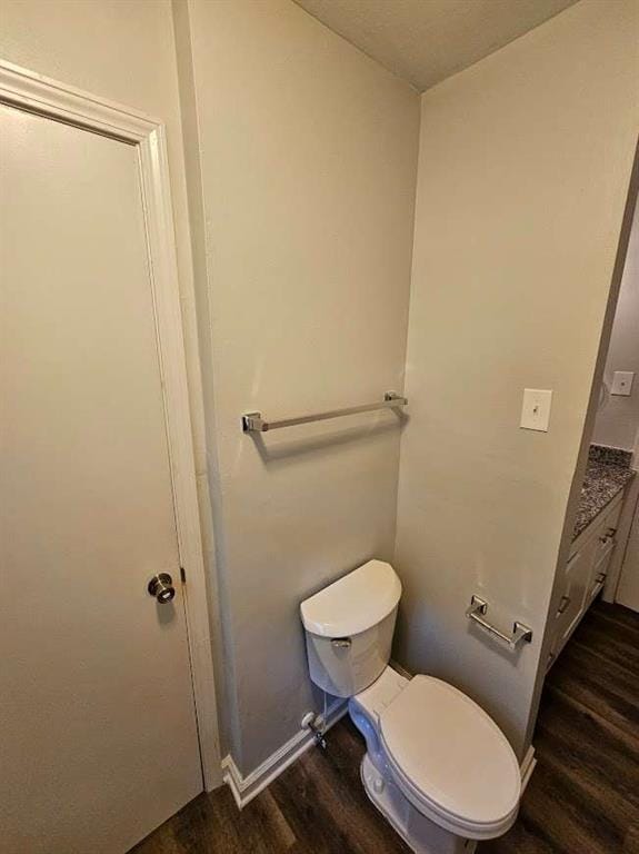 bathroom with toilet, baseboards, and wood finished floors