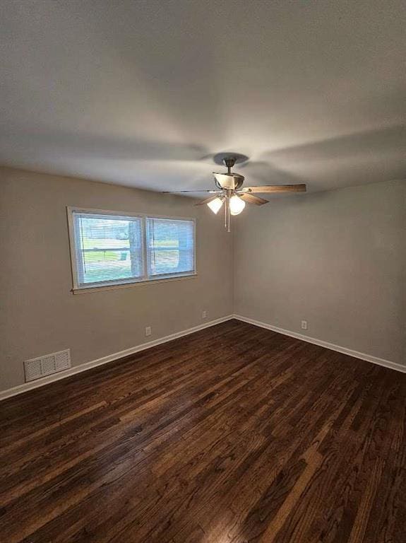 empty room with dark wood finished floors, visible vents, ceiling fan, and baseboards