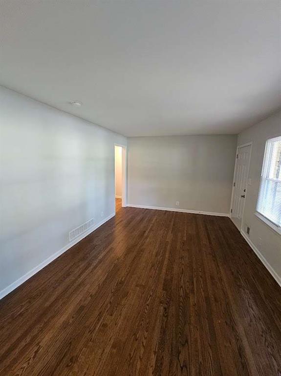 unfurnished living room with dark wood finished floors, visible vents, and baseboards