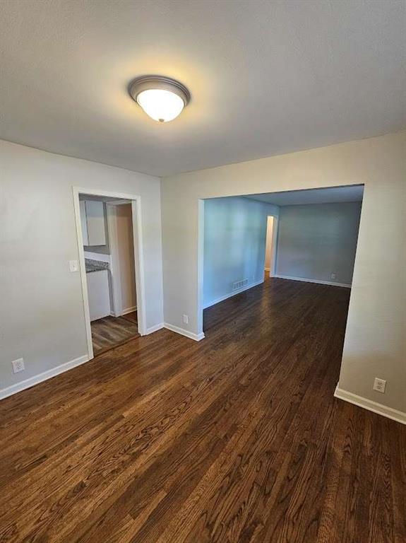 spare room with visible vents, baseboards, and wood finished floors