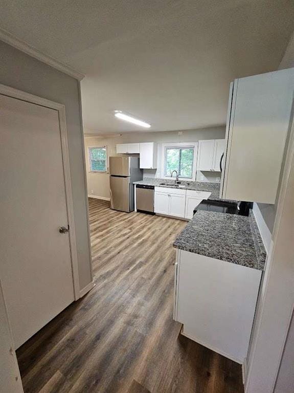 kitchen featuring a sink, wood finished floors, white cabinetry, stainless steel appliances, and a healthy amount of sunlight