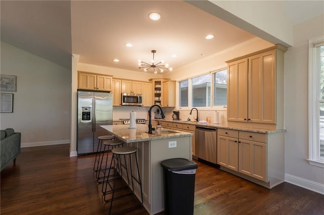 kitchen featuring dark hardwood / wood-style flooring, light stone counters, stainless steel appliances, sink, and a kitchen island