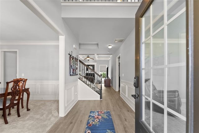 entrance foyer featuring a wainscoted wall, visible vents, a decorative wall, stairway, and wood finished floors