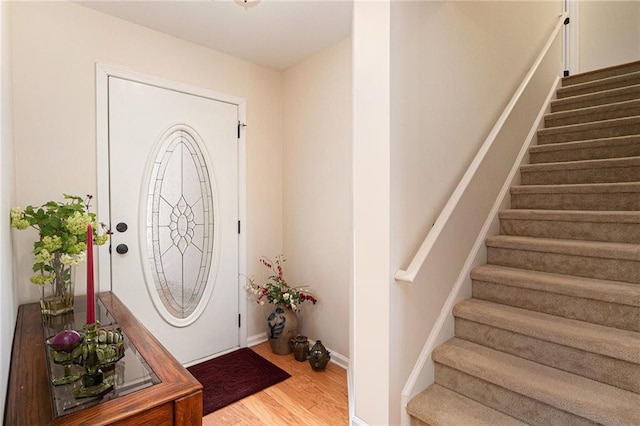 foyer entrance with baseboards, wood finished floors, and stairs