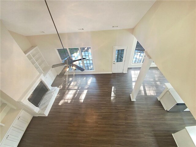 unfurnished living room featuring ceiling fan, dark wood-type flooring, and a high ceiling