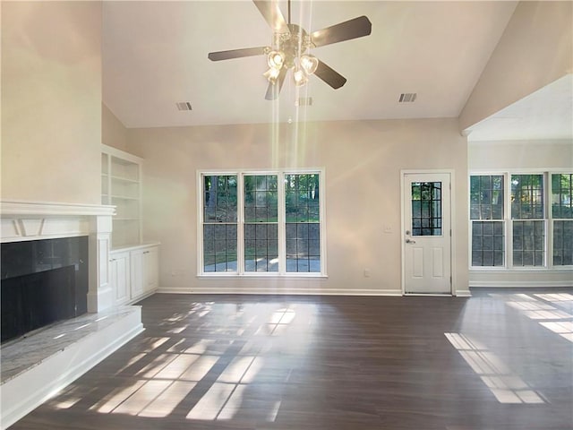 unfurnished living room with a high end fireplace, vaulted ceiling, ceiling fan, and dark wood-type flooring