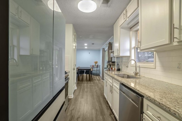 kitchen with dishwasher, white cabinetry, and sink