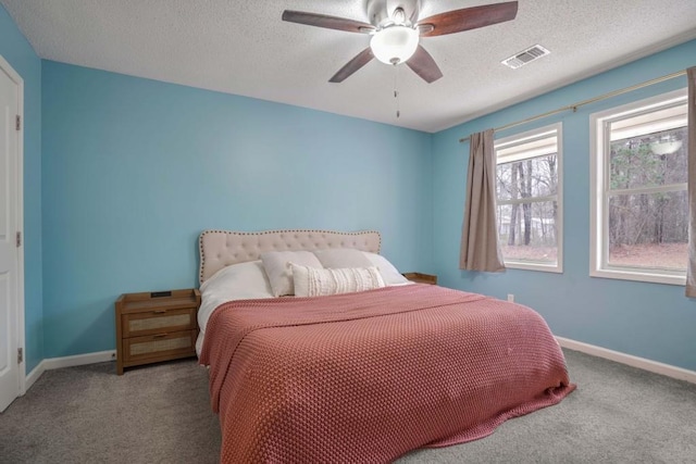 carpeted bedroom with ceiling fan and a textured ceiling