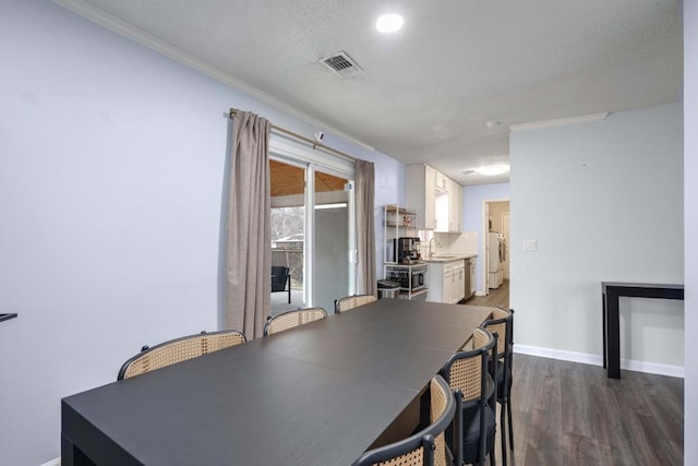 dining space with crown molding, sink, dark wood-type flooring, and a textured ceiling