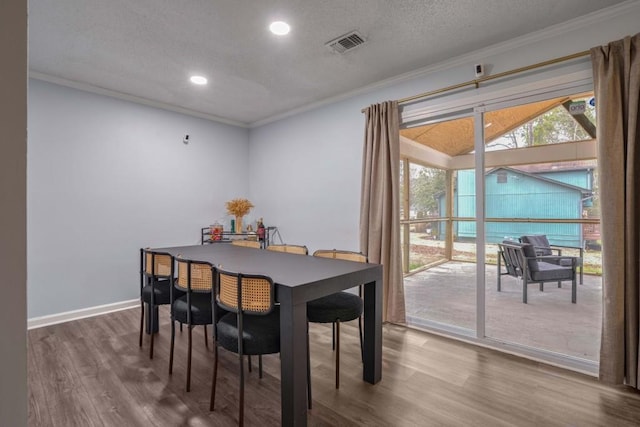 dining area with a textured ceiling, crown molding, and dark wood-type flooring