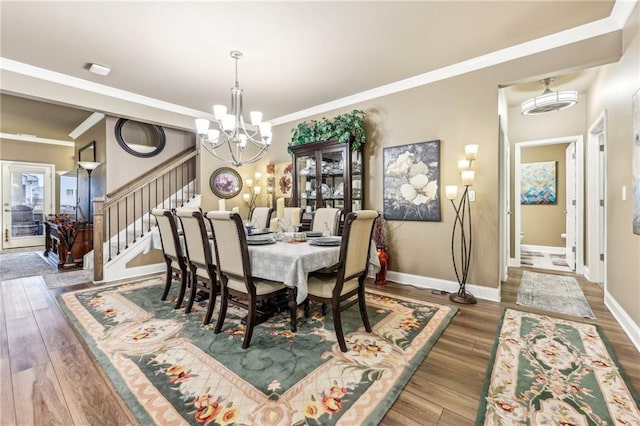 dining room with dark hardwood / wood-style flooring, ornamental molding, and a notable chandelier