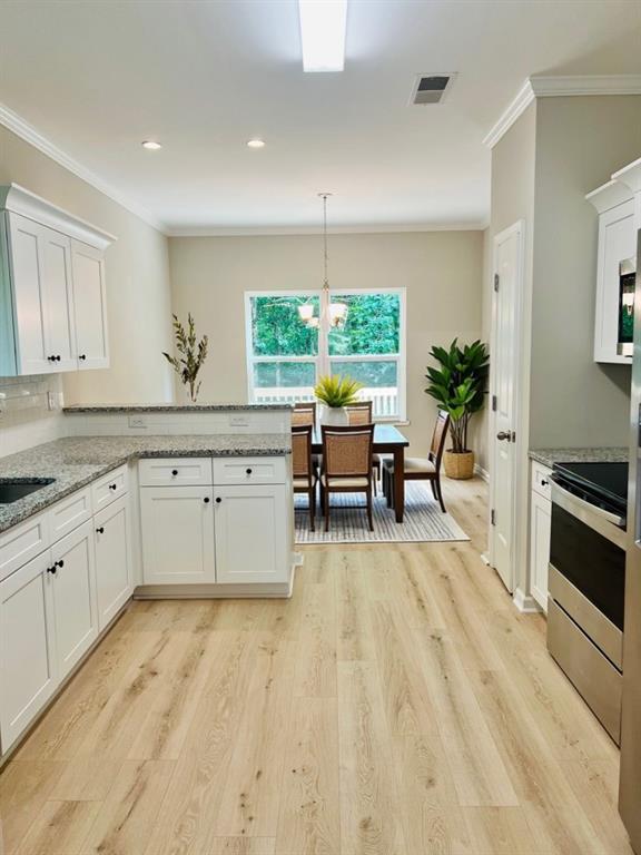 377 Fieldcrest Dr, Dallas, GA 30132 - kitchen with electric range, ornamental molding, white cabinetry, a peninsula, and light wood-type flooring