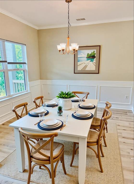 377 Fieldcrest Dr, Dallas, GA 30132 - dining space featuring light wood-type flooring, a chandelier, ornamental molding, a decorative wall, and a wainscoted wall