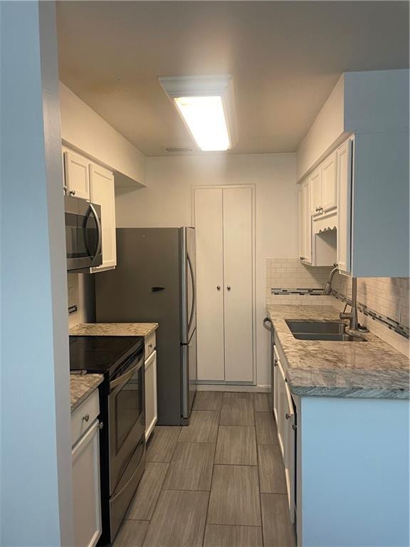 23210 Plantation Dr NE, Atlanta, GA 30324 - kitchen with appliances with stainless steel finishes, white cabinetry, a sink, and backsplash