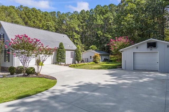 view of front of house with an outdoor structure, concrete driveway, a garage, and a front lawn
