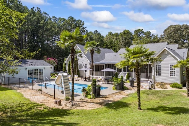 view of swimming pool with a water slide, a sunroom, a yard, and a patio