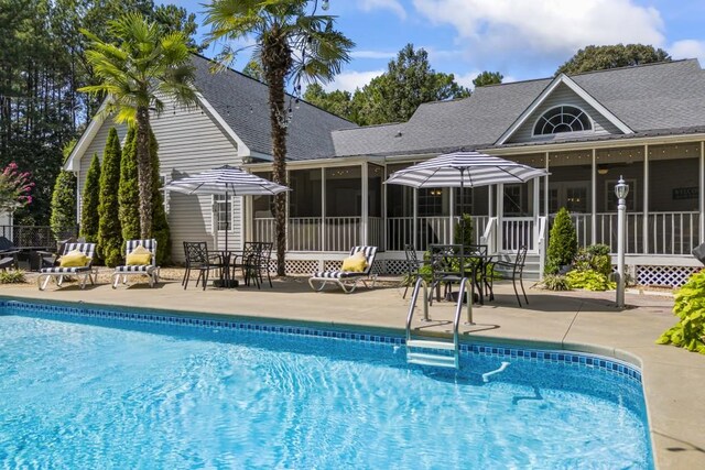 outdoor pool featuring a sunroom, fence, and a patio