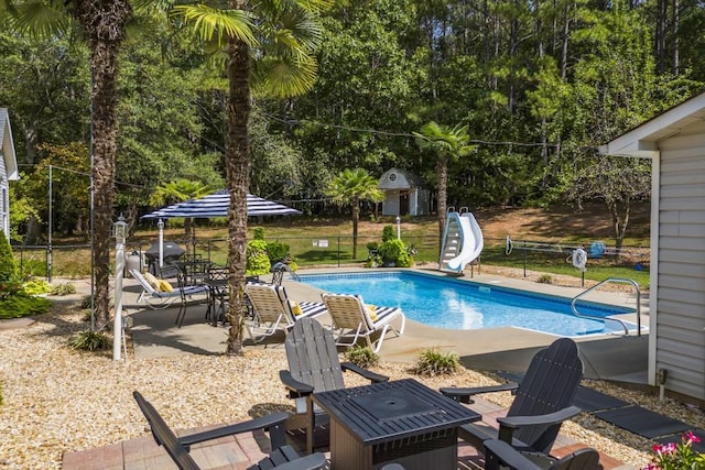 view of swimming pool with a water slide, a patio, and a shed