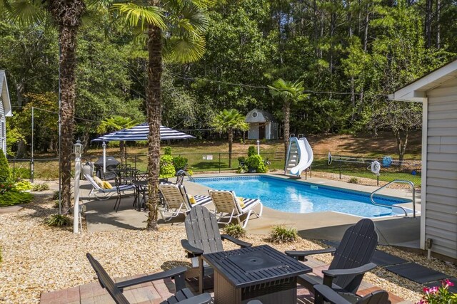 view of pool featuring a patio, fence, a fenced in pool, and a water slide