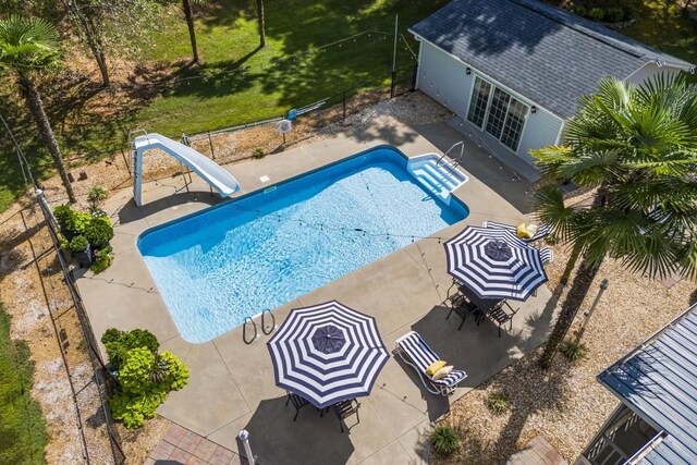 view of swimming pool with a fenced backyard, a fenced in pool, a water slide, and a patio