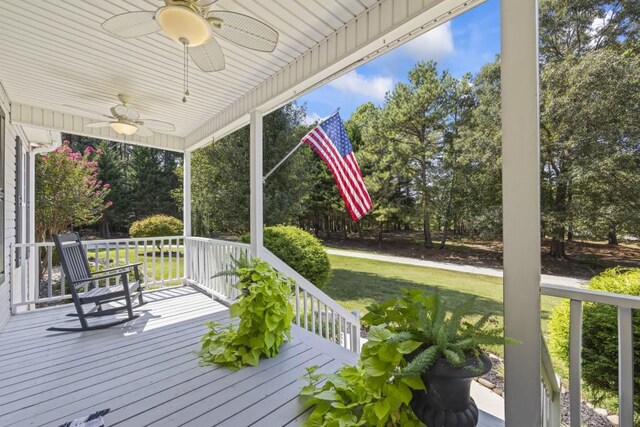 wooden terrace with ceiling fan and a yard