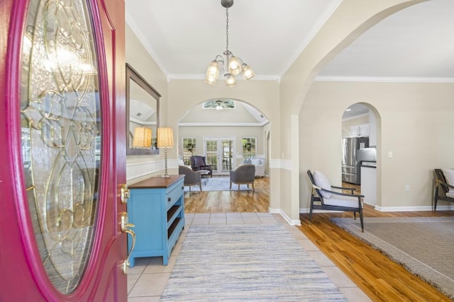 foyer entrance with crown molding, light hardwood / wood-style flooring, and a chandelier